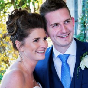 The bride captured with her brother under the portico with gorgeous lighting behind at her Dorton House wedding