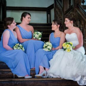 The bride sits on the staircase for an informal pose with her bridesmaids at her Dorton House wedding