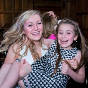 Fun wedding capture taken on the dance floor of a lady lifting a young girl in her arms at Dorton House in Buckinghamshire