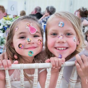 Two smiling flower girls covered in transfer stickers smile for the camera at this Dorton House marquee wedding in Buckinghamshire