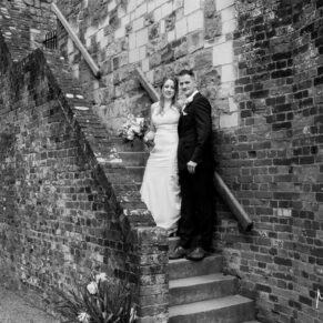 The bride and groom climb the steps to the summit of Farnham Castle on their wedding day