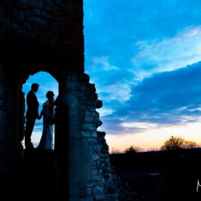 Dramatic pose of the newlyweds at the summit of Farnham Castle captured during golden hour after a climb up the many steps