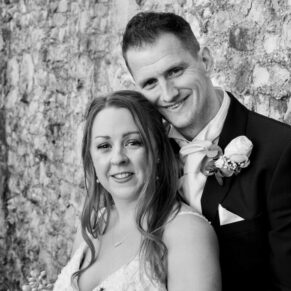 The newlyweds pose for my camera against a historic stone wall on their wedding day
