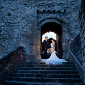 Photography of the newlyweds captured with low evening sunlight in one of the ancient doorways at the historic Farnham Castle wedding venue
