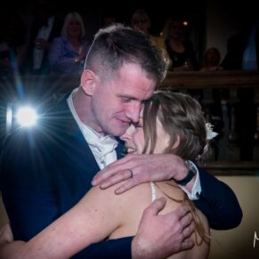 Photography of the newlyweds embracing during their first dance at their Farnham Castle evening wedding reception