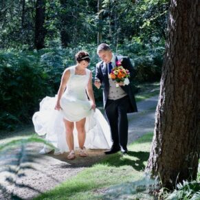 The bride and groom walking through a woodland setting at their Buckinghamshire marriage venue