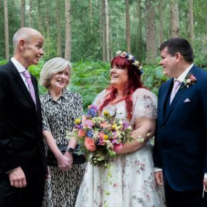 A natural chatting pose of the newlyweds with their parents captured in a woodland setting at this Buckinghamshire marriage