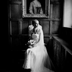 A classic black and white pose of the bride beside a window in the Great Hall