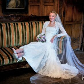 The bride sits down on a comfy stripped sofa with oak panelling behind her