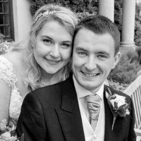 The smiling newlyweds captured in a close-up black and white pose in the gardens