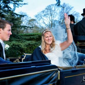 The newlyweds wave to their guests as their horse and carriage pulls out of the driveway