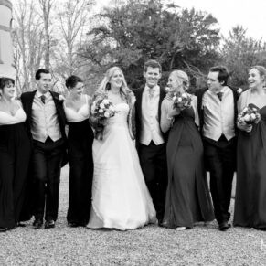 The newlyweds giggling and walking along with their ushers and bridesmaids in the gardens on a brisk winter's day