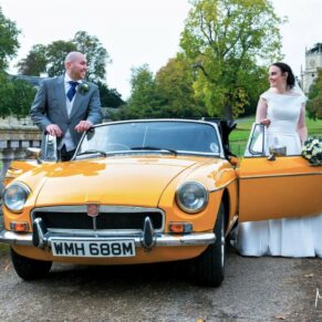 The newlyweds beside their vintage car on the bridge at Hartwell House