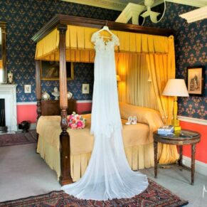 The bride's gown hanging from the four poster in the bridal suite at Hartwell House Hotel in Buckinghamshire
