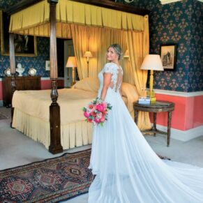 The bride captured full length in the bridal suite with her four poster bed at Hartwell House Hotel