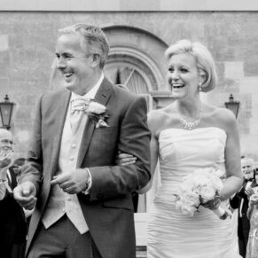The smiling newlyweds walking through their confetti aisle just after the civil ceremony at Hartwell House Hotel