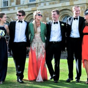 Some of the young wedding guests walking arm in arm through the gardens at Hartwell House Hotel