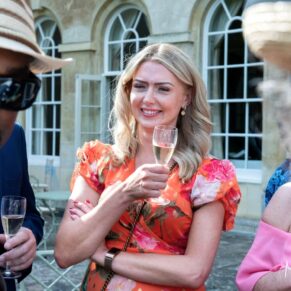 Candid moment captured during the summer wedding drinks reception of three friends on the terrace at Hartwell House Hotel