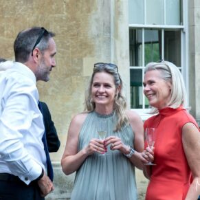 Reportage image capture of three smiling guests captured during the wedding drinks reception on the terrace at Hartwell House