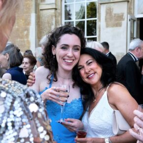 Relaxed image capture of two ladies having a hug during the wedding drinks reception on the garden terrace at Hartwell House