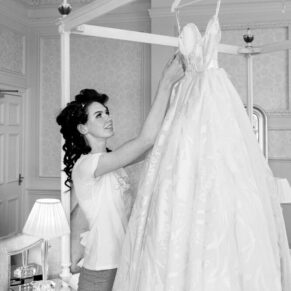 The bride makes some final adjustments to her gown in the bridal suite for this black and white capture at her Hedsor House wedding