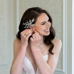 The bride making adjustments to her ear rings in the bridal suite before her wedding ceremony at Hedsor House