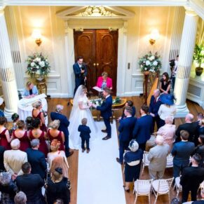 Looking down on the packed wedding ceremony from the balcony in the Great Hall at Hedsor House