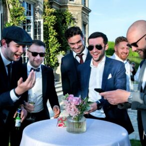 Some lively friends watch a big game of footie on their phone at this Hedsor House wedding