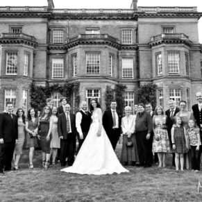 Black and white family wedding group pose in front of Hedsor House