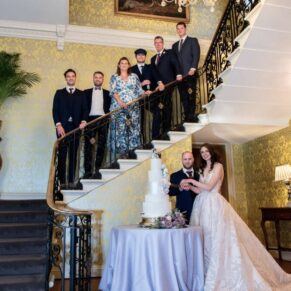 The family join the newlyweds for the wedding cake cutting on the staircase at Hedsor House