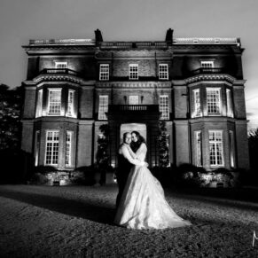 Dramatic dusk shot of the newlyweds at the front of Hedsor House after night-fall on their wedding day