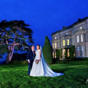 Night time pose with the bride and groom stood in front of Hedsor House and their famous cedar tree at dusk whilst being illuminated by my dramatic floodlighting