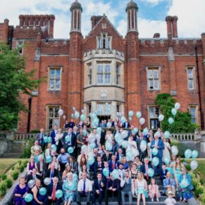 Large group pose with a fun balloon release on the steps of the main house