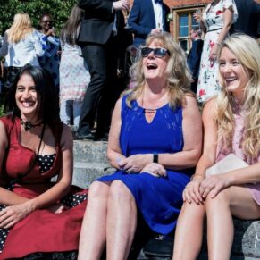 Photography of wedding guests relaxing on the hotel steps whilst enjoying a giggle during the drinks reception at the Latimer Estate