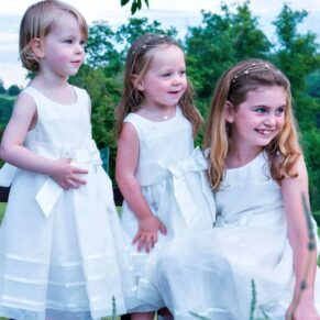 The flower girls playing up to the camera whilst they all standing on a bench behind a lavender border for this wedding on the Latimer Estate