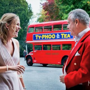 The bridesmaid chats to the toastmaster with a red London bus positioned behind them