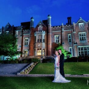 Dramatic floodlit night shot of the newlyweds outside the main house at their Latimer Estate wedding