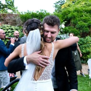 The bride receives a big hug from her brother during the drinks reception in the walled gardens of the venue