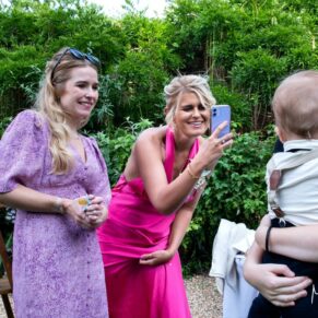 Candid moment between two ladies and the pageboy captured during the drinks reception in the walled gardens