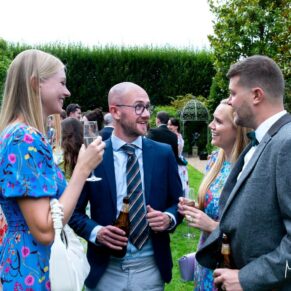Fun candid shot of four guests captured chatting in the gardens during the drinks reception