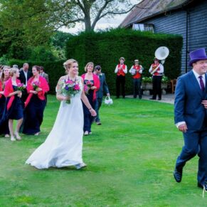 Micklefield Hall Wedding Photography - the bridal party wandering through the gardens with the barn behind them