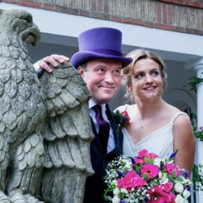 Micklefield Hall Wedding Photography - the newlyweds with the stone eagle in the gardens