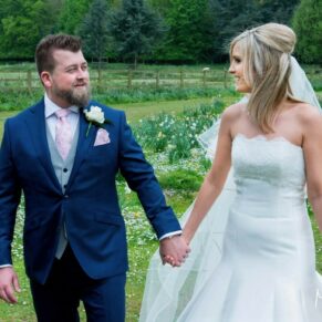The bride and groom walking hand in hand in the wonderful gardens of the abbey