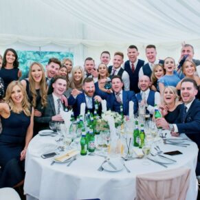 Large group of lively friends captured at their table in the marquee during the meal