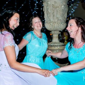 Three bridesmaids dancing the night away at The Dairy with beaming smiles and gorgeous fairy lights as the backdrop