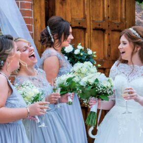 The bride giggling with her bridesmaids at the main entrance doorway at The Dairy