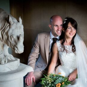 The newlyweds strike a dramatic pose beside the stone rhinoceros at The Dairy on the Waddesdon Estate