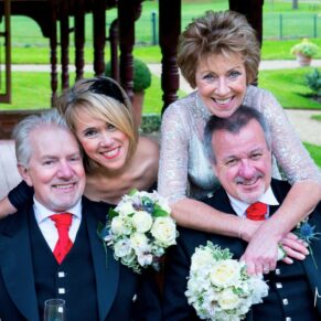 Relaxed hugging pose between the smiling newlyweds and their best man and bridesmaid during this informal wedding at The Dairy on the Waddesdon Estate