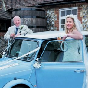 Old Luxters Wedding Photography - the bride and groom pose with their vintage mini