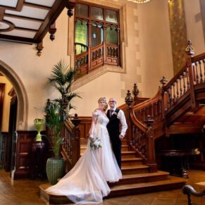 The newlyweds pose for the camera on the grand staircase at their Pendley Manor Hotel wedding
